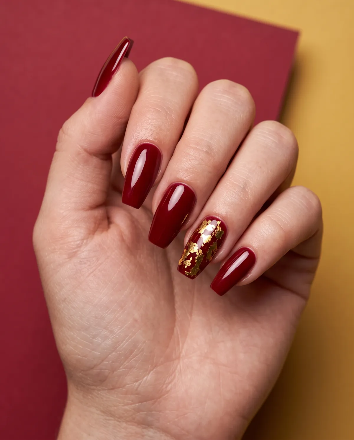 Gilded Noel — coffin christmas nails with do a deep red gel base with gold foil accents on one coffin-shaped nail as a statement