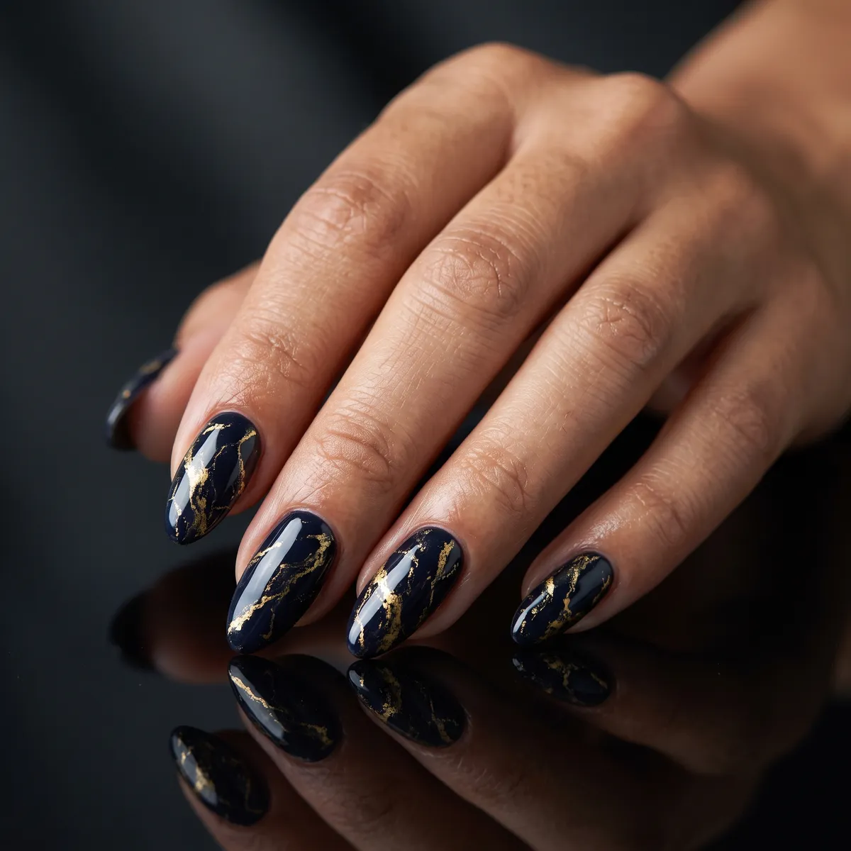 Midnight Gold Marble — almond halloween nails with navy-black gel base marbled with gold foil veins, almond shape, high-gloss finish…